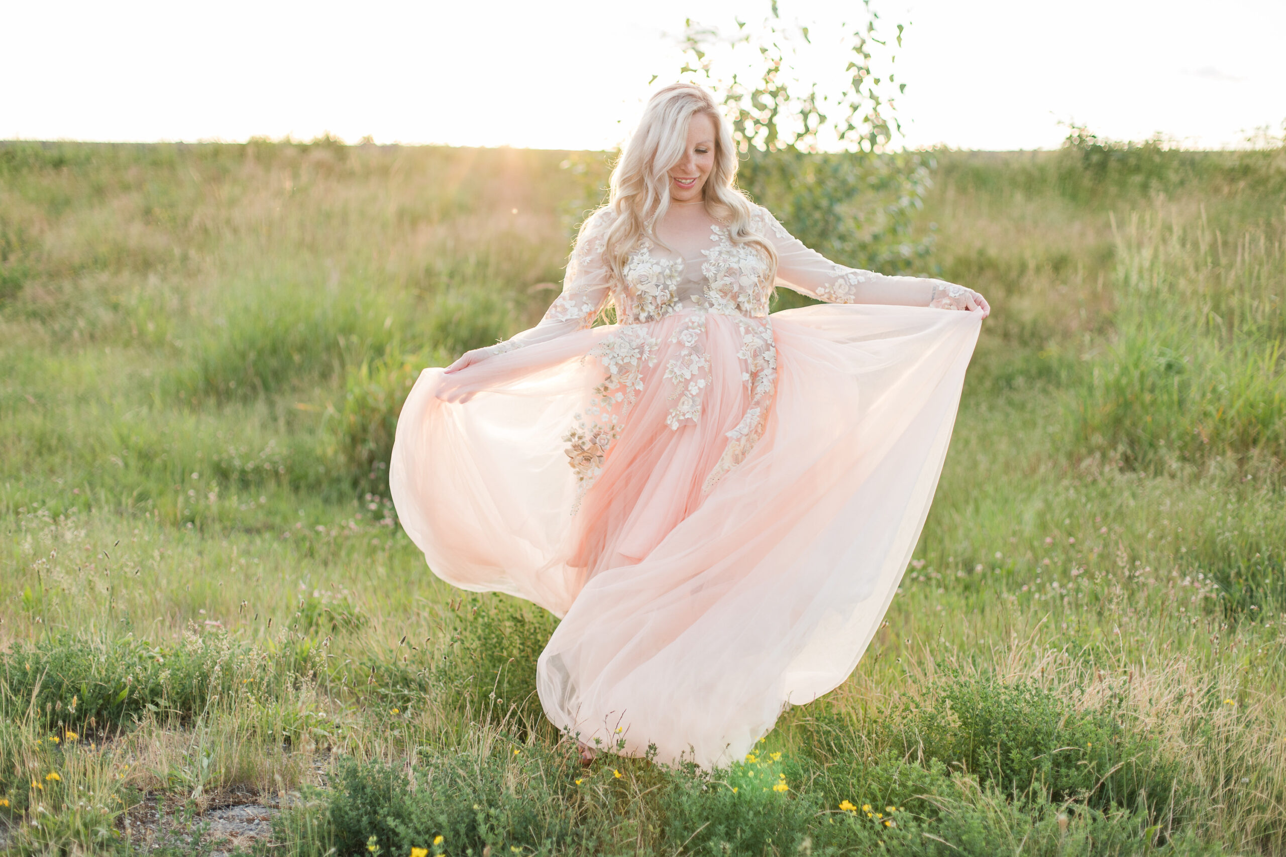 mom to be in pink maternity gown twirling in a field Kelowna doulas