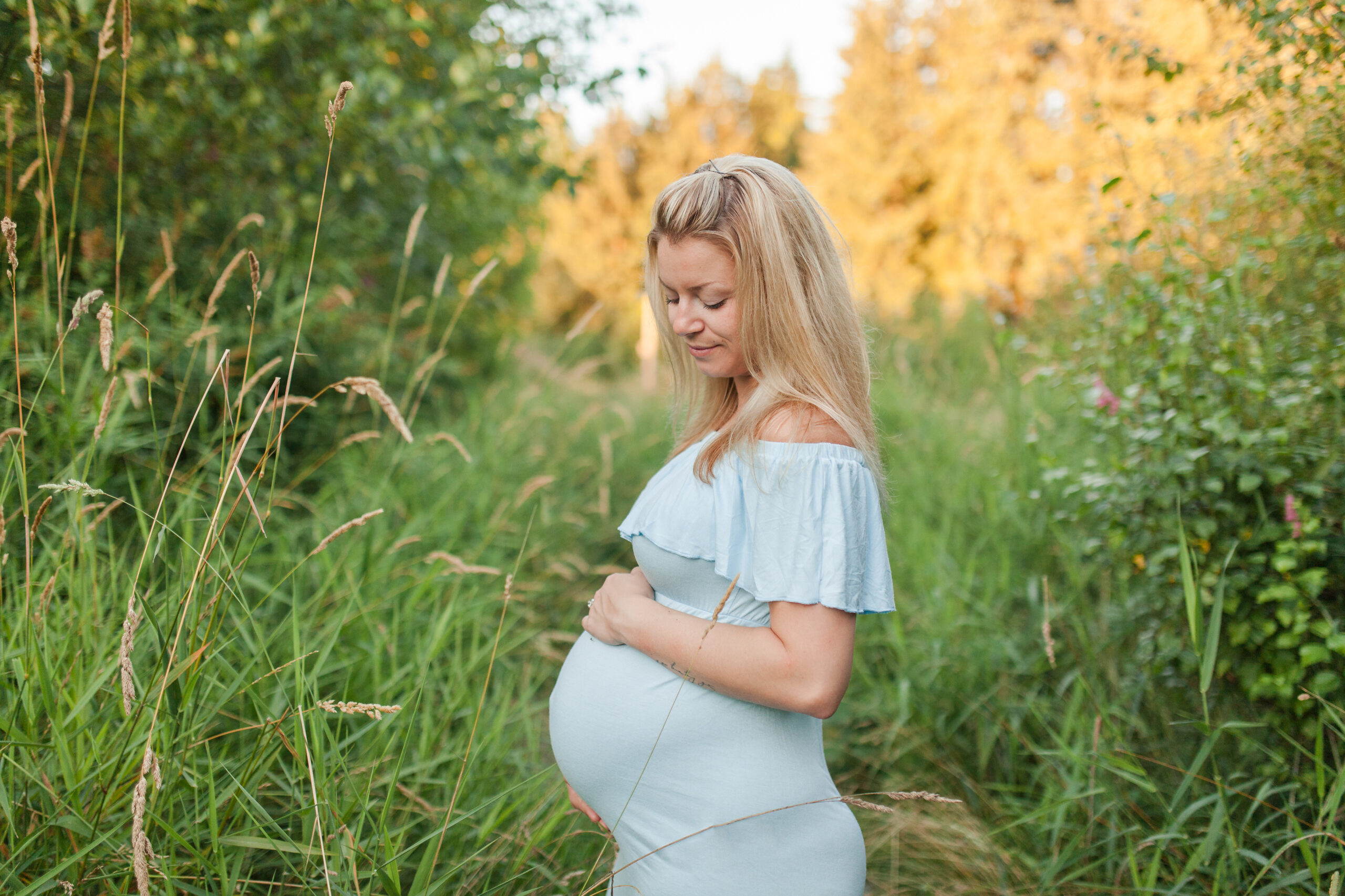 mom to be in blue maternity gown in a field Malachite Midwives