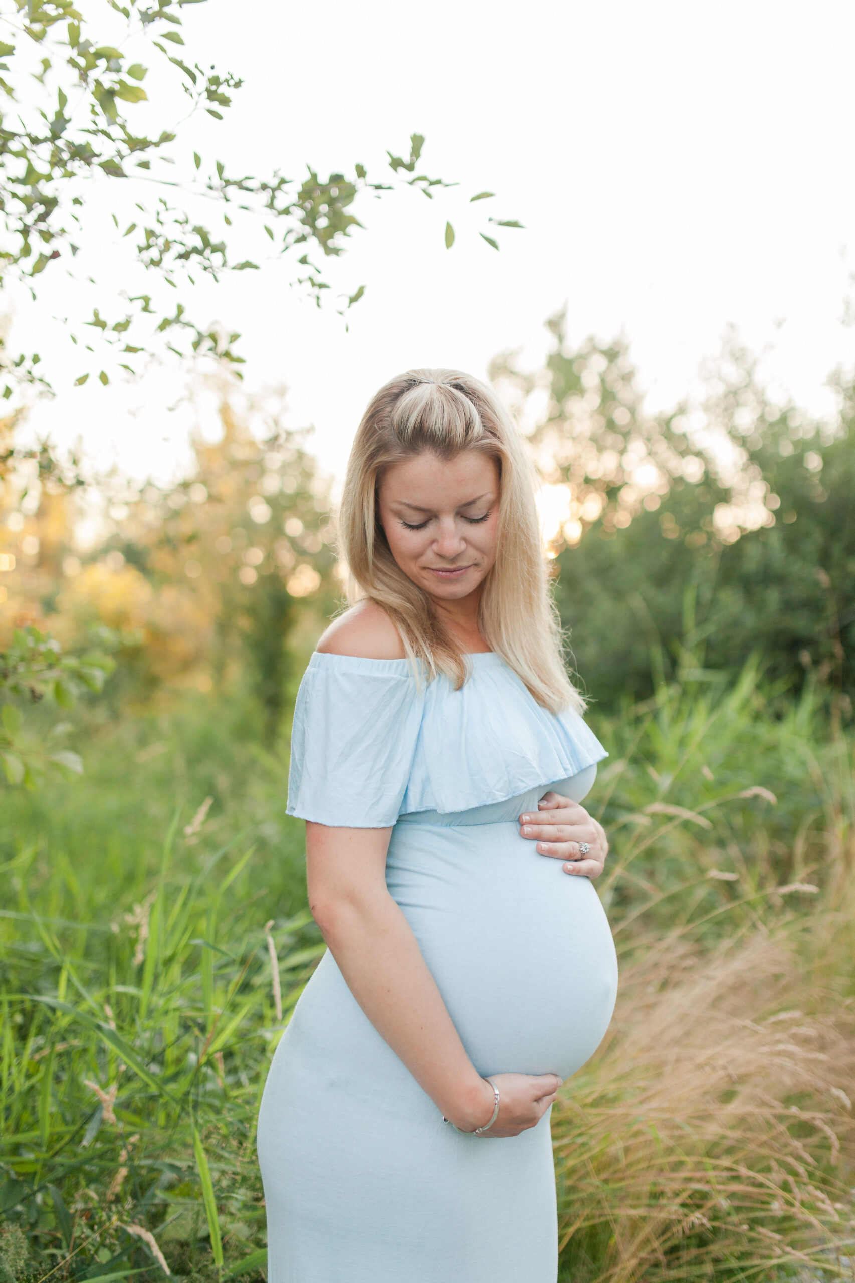 pregnant woman in blue gown looking down at her bump