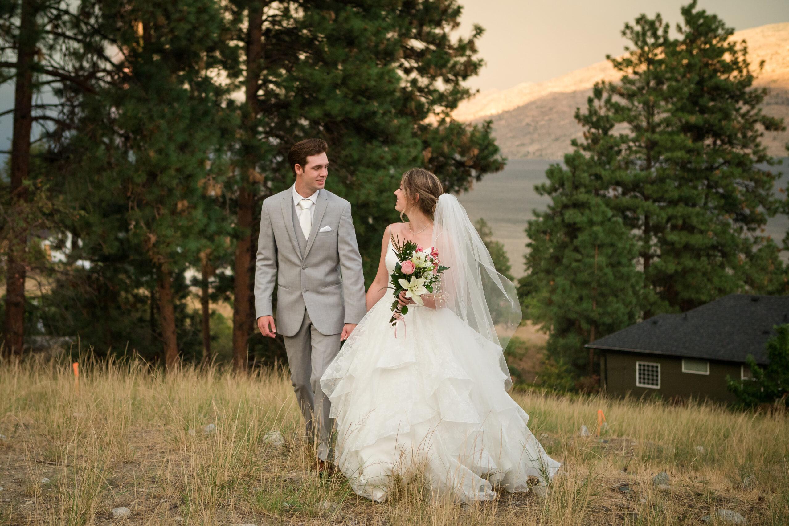 bride and groom walking hand in hand in a field at Okanagan Wedding Venues