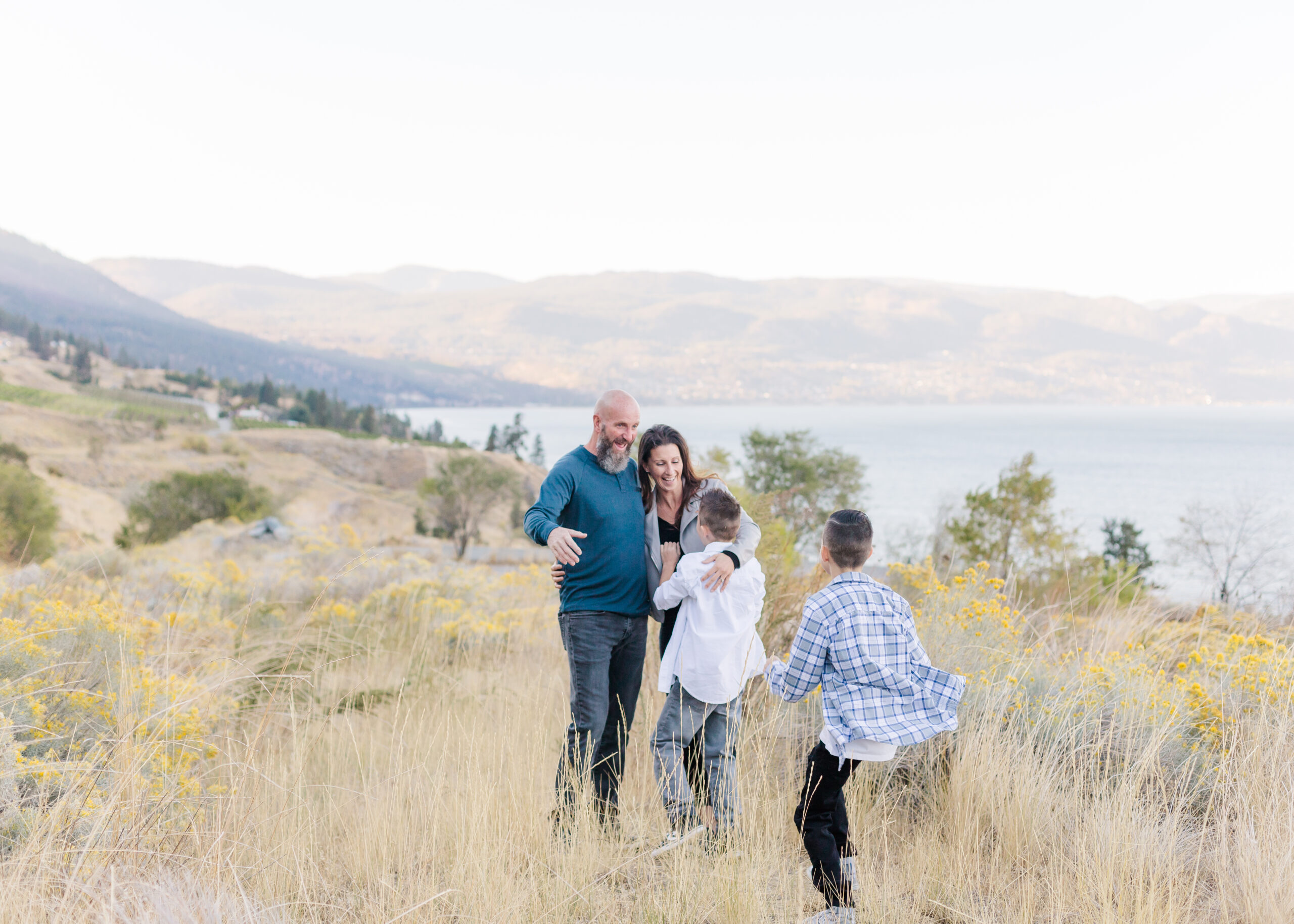 kelowna family of four running and playing in a field