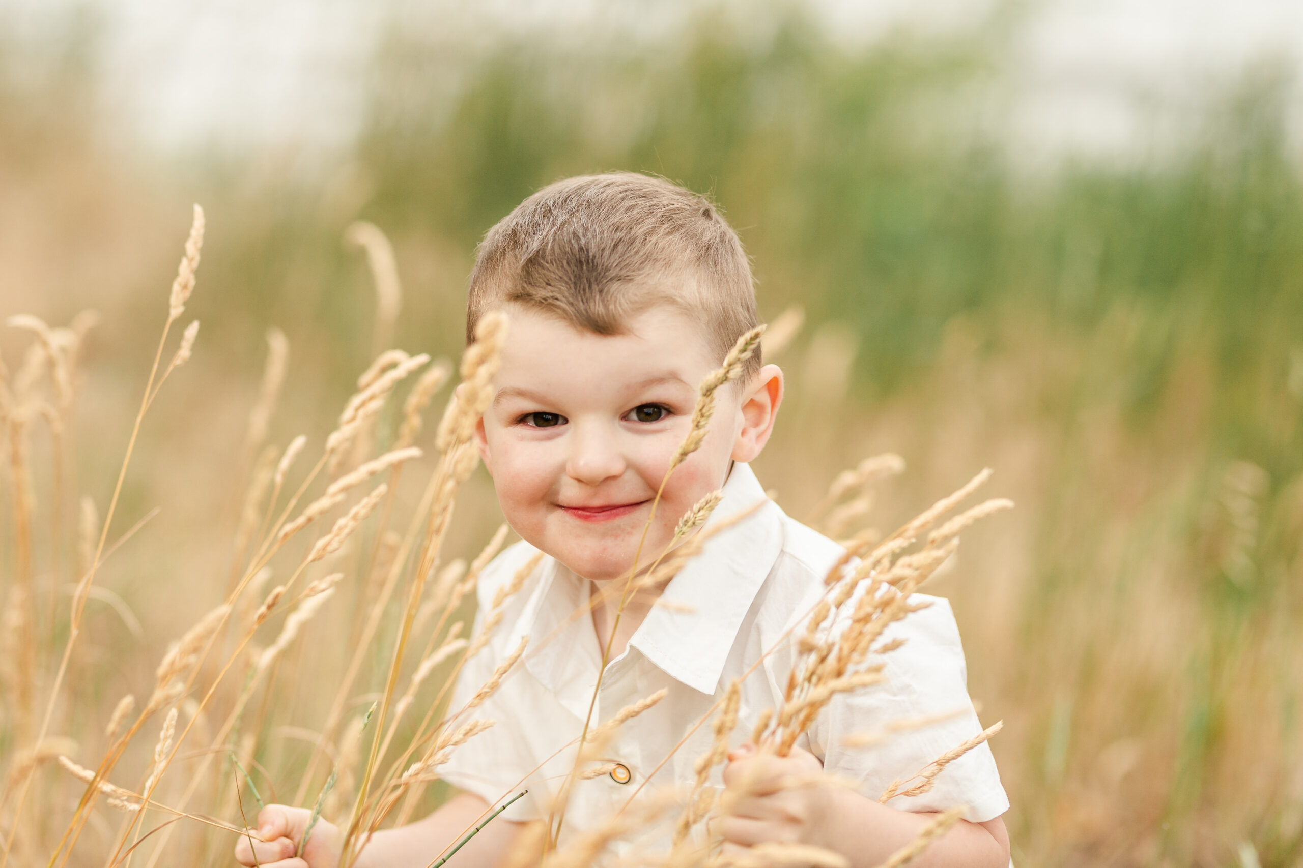 little boy peeking in through the grass in a field