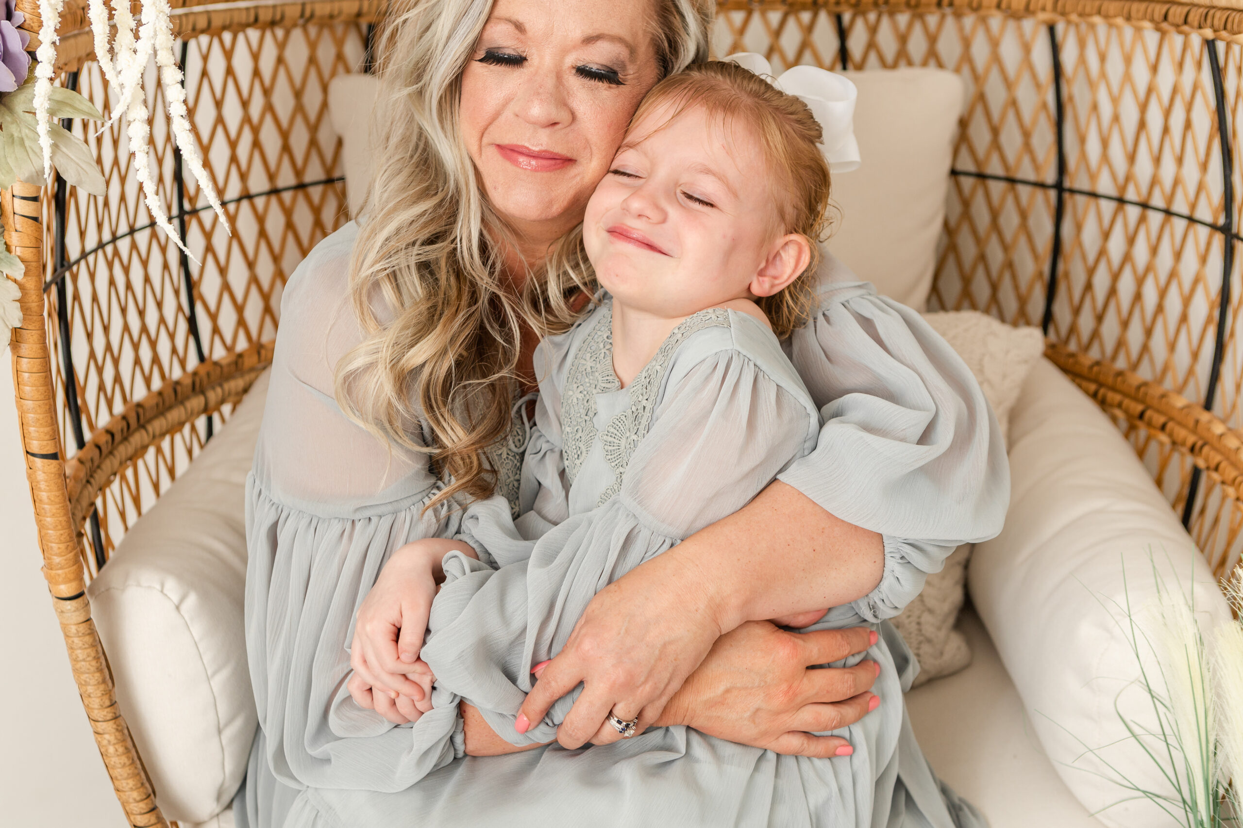 mom and daughter wearing matching dresses snuggling in a floral chair